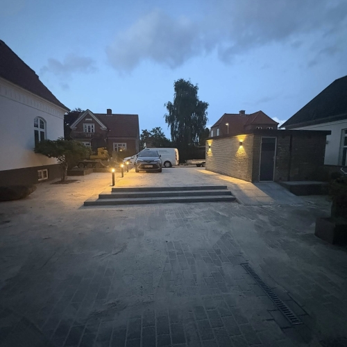 Stor indkørsel med nylagt brolægning og belysning ved trin, Bramming.