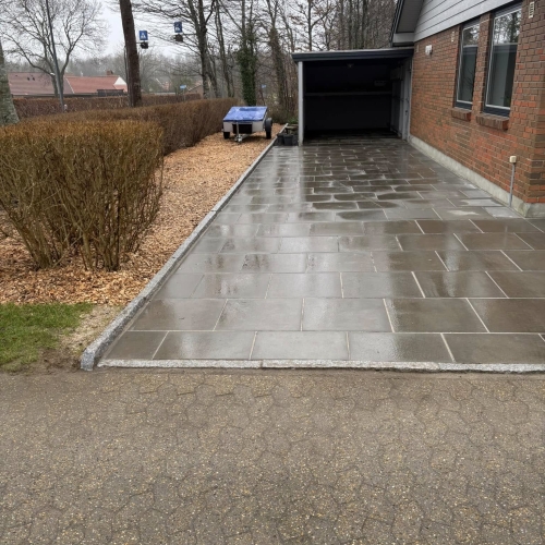 Ny belægning af indkørsel i Bramming med mørke betonfliser og ny kantafslutning.