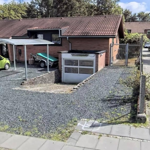 Indkørsel i Vejen med grus og garage, klar til udskiftning af belægning.