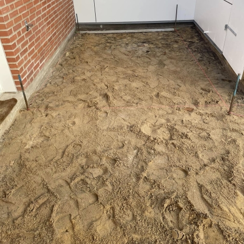 Forberedelse til flisearbejde i gårdhave i Esbjerg med afrettet sandbund.
