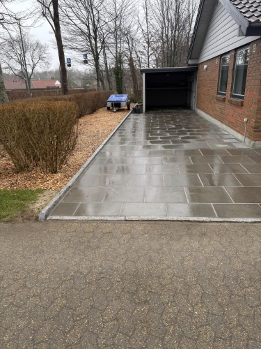 Ny belægning af indkørsel i Bramming med mørke betonfliser og ny kantafslutning.