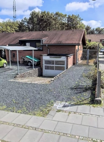 Indkørsel i Vejen med grus og garage, klar til udskiftning af belægning.