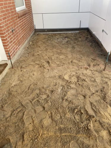 Forberedelse til flisearbejde i gårdhave i Esbjerg med afrettet sandbund.