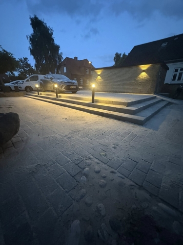 Elegant brolægning foran trappe og parkering med lys, udført af brolægger i Bramming.