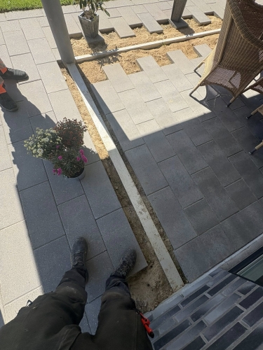 Flisearbejde hvor nye fliser lægges omkring terrasseområde i Bramming.