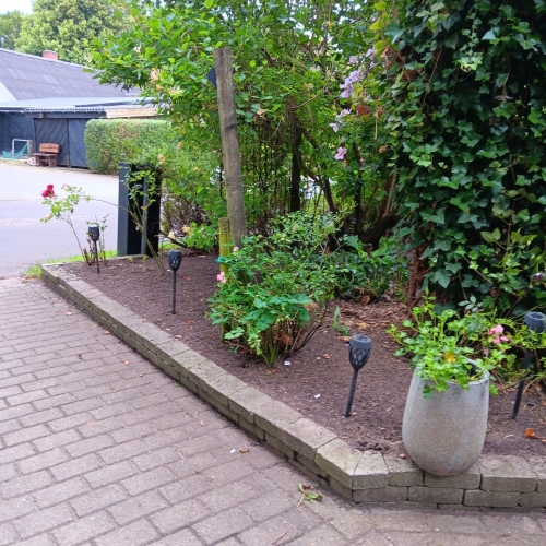 Opryddet havebed med krukker og nye planter efter haveservice i Grimstrup.