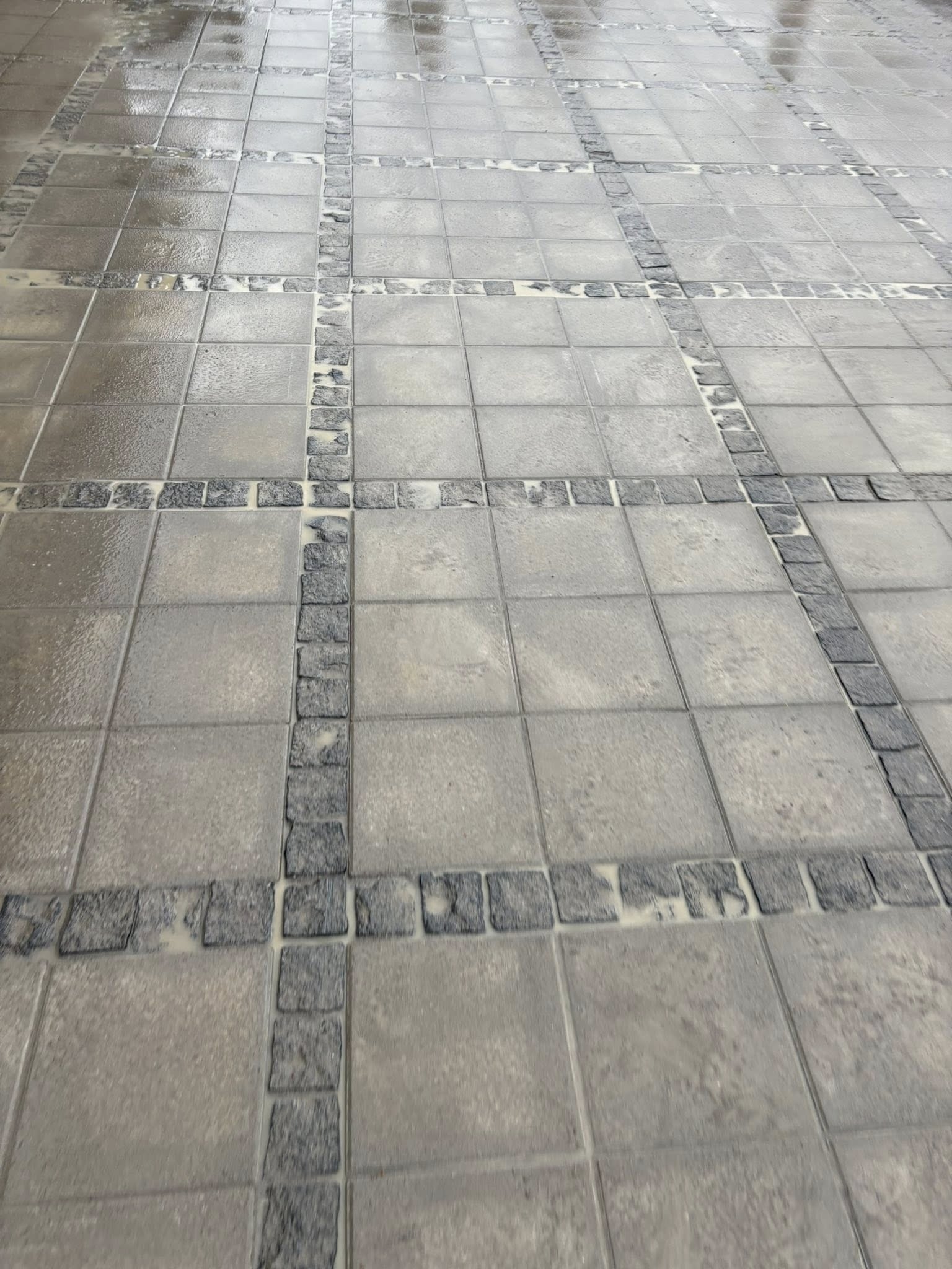Detalje af kvadratisk flisebrolægning med mørke kantsten i Esbjerg.